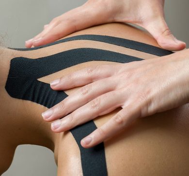 Physiotherapist putting on black kinesio tape on woman patients